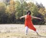 Christine Dion rayonnante danse dans un champ, les bras ouverts et le sourire éclatant.