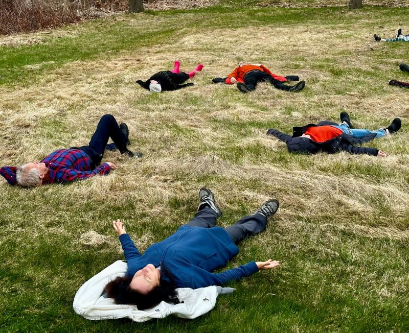 Le groupe allongé dans l'herbe, bras ouverts, après la pratique.