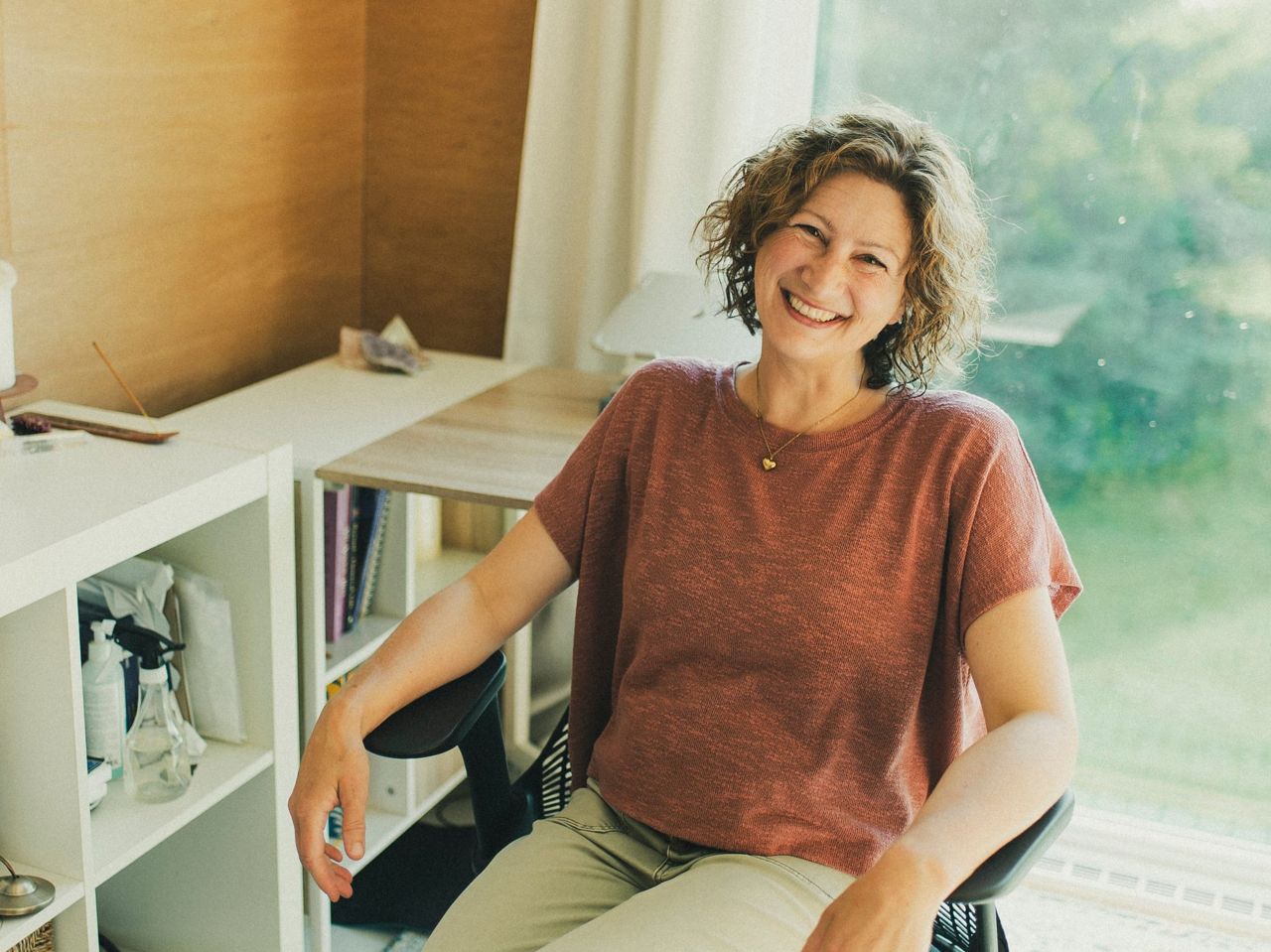 Christine Dion souriante à son bureau, dans la lumière naturelle de Saint-Jean-Port-Joli.