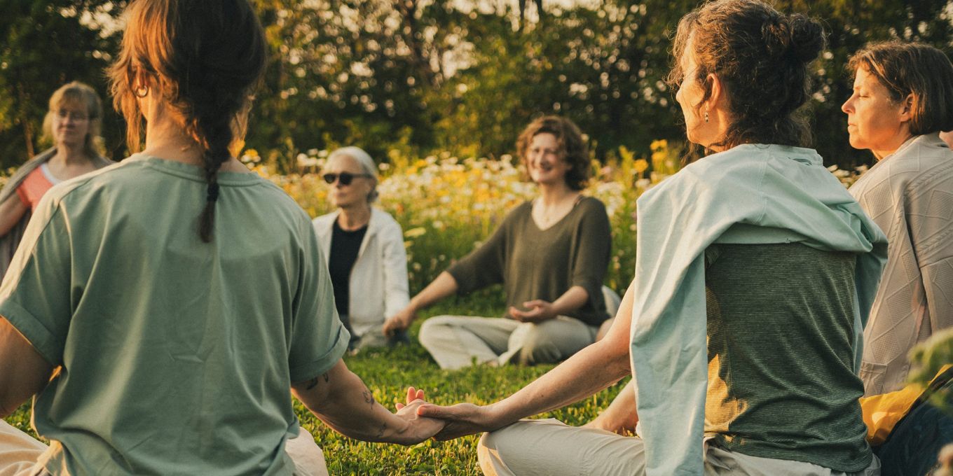 Groupe assis en cercle dans un champ fleuri, en méditation