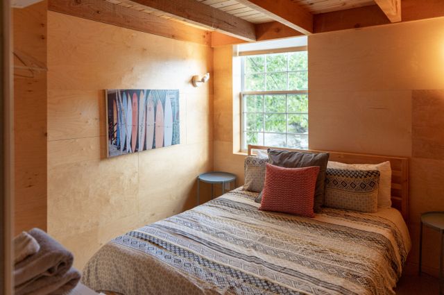 Chambre chaleureuse avec lit queen, poutres apparentes et tableau coloré